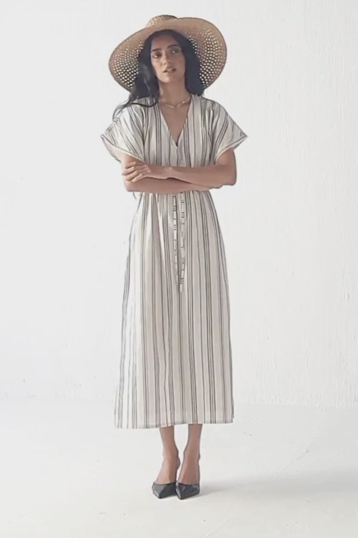 Model showcases Reistor striped maxi gathered dress with side slits, styled with a straw hat, presenting a front pose followed by a back pose to display the dress’s silhouette, gathered detailing, and flowing fabric.