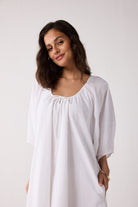 Woman wearing a white dress against a plain background