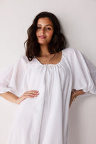 Woman wearing a white dress against a plain background