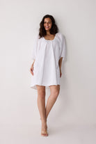 Woman wearing a white dress against a plain background