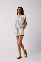 Woman wearing a striped shirt and shorts set against a plain background
