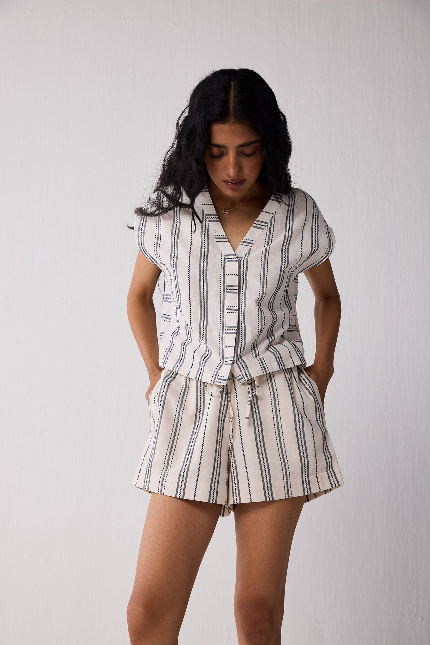Woman wearing a striped shirt and shorts set against a plain background