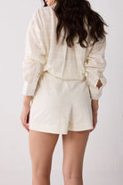 Person wearing a white outfit with a jacket and shorts on a plain background