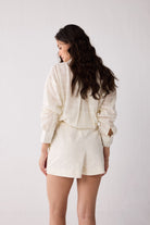 Woman wearing a white shorts against a plain background