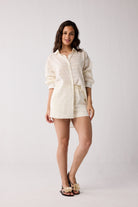 Woman wearing a off white colored outfit on a white background