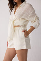 Woman wearing a white outfit with a matching top and shorts on a plain background