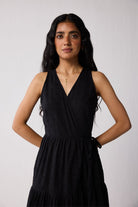 Woman wearing a black sleeveless dress against a white background