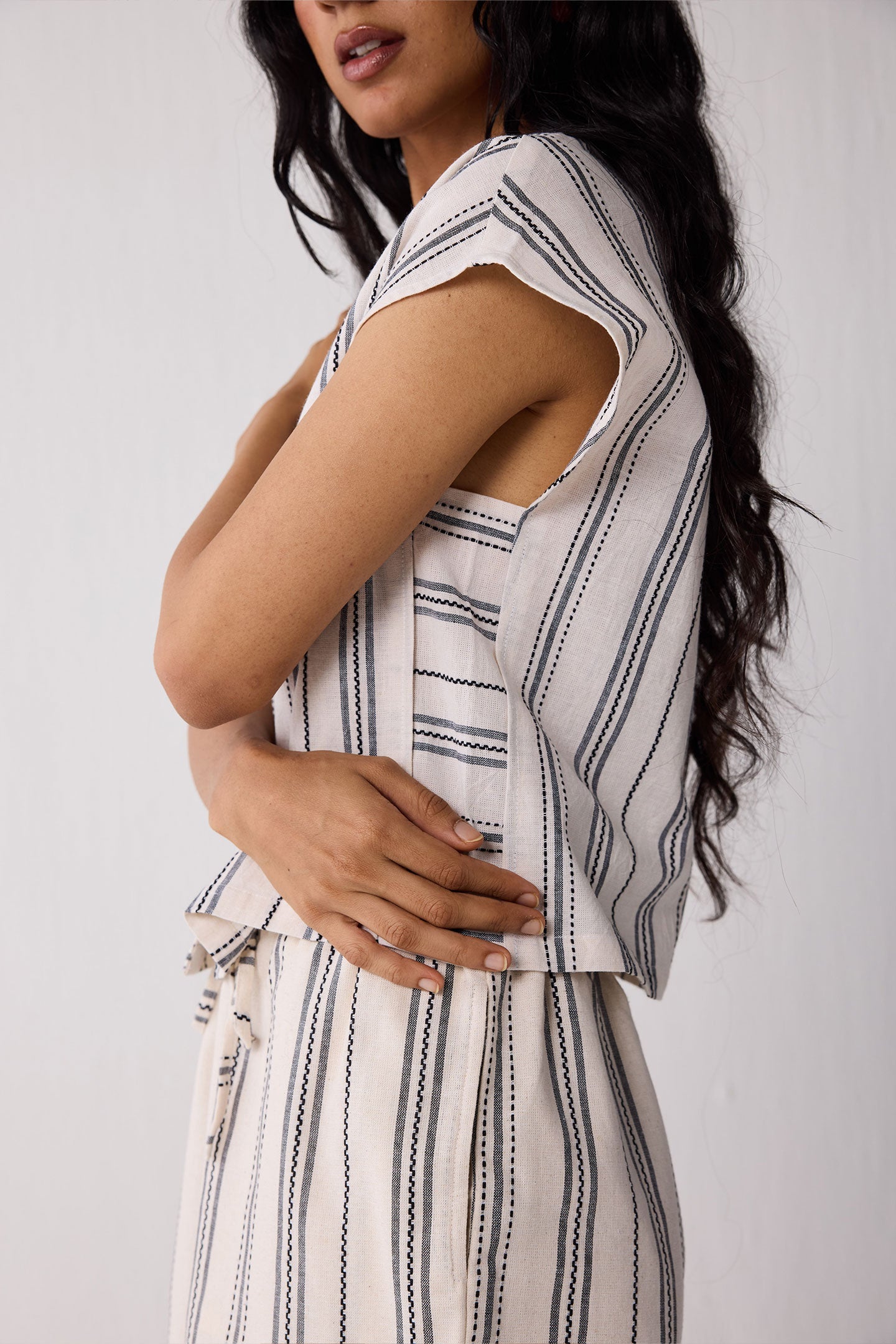 Woman wearing a sleeveless striped top and shorts against a white background