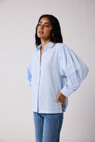 Woman wearing a light blue striped shirt and jeans on a white background