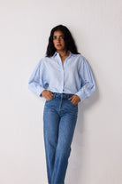 Woman wearing a light blue striped shirt and jeans on a white background