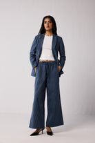 Woman wearing a blue pinstripe suit with a white top against a plain background