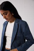 Woman wearing a blue pinstripe blazer over a white top against a plain background