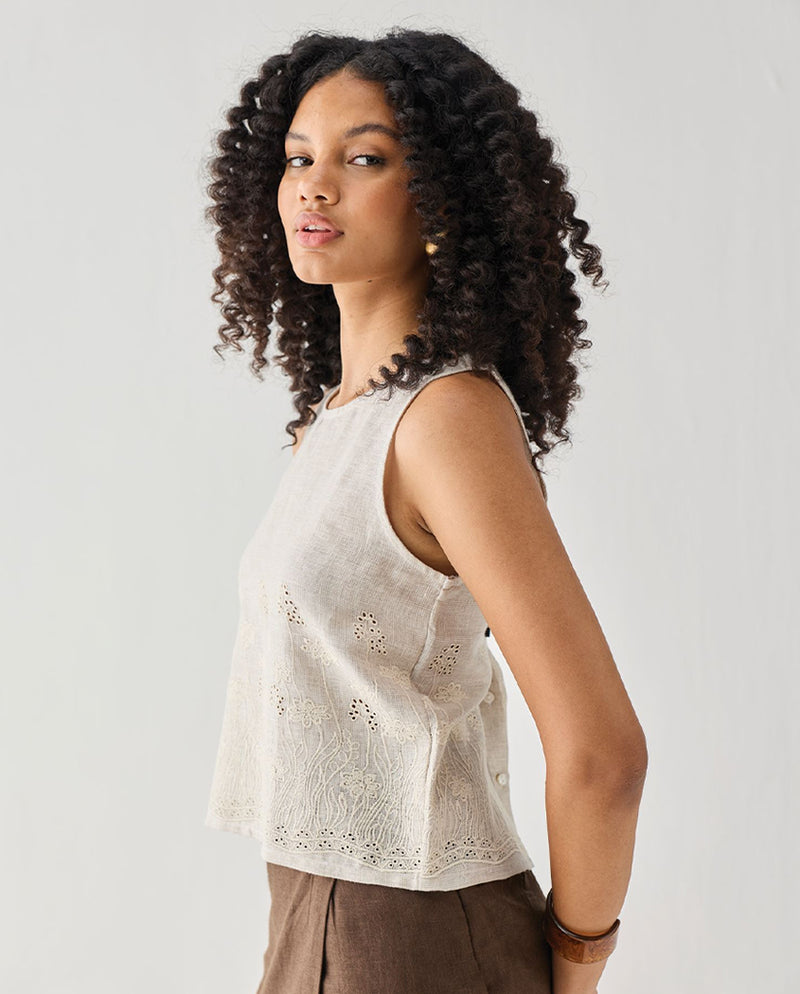 Woman wearing a sleeveless top with lace details on a plain background