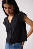 Woman wearing a black sleeveless shirt and blue jeans on a white background