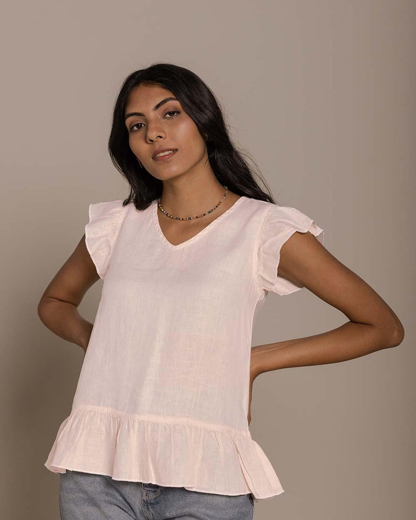 blush pink top with ruffled sleeves and ruffled border. The top has a v neck and buttons not the back.